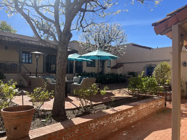 Brick courtyard terrace with terracotta pots and teal umbrellas